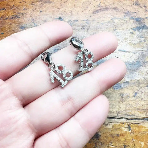 Two silver ''' charm pendants.