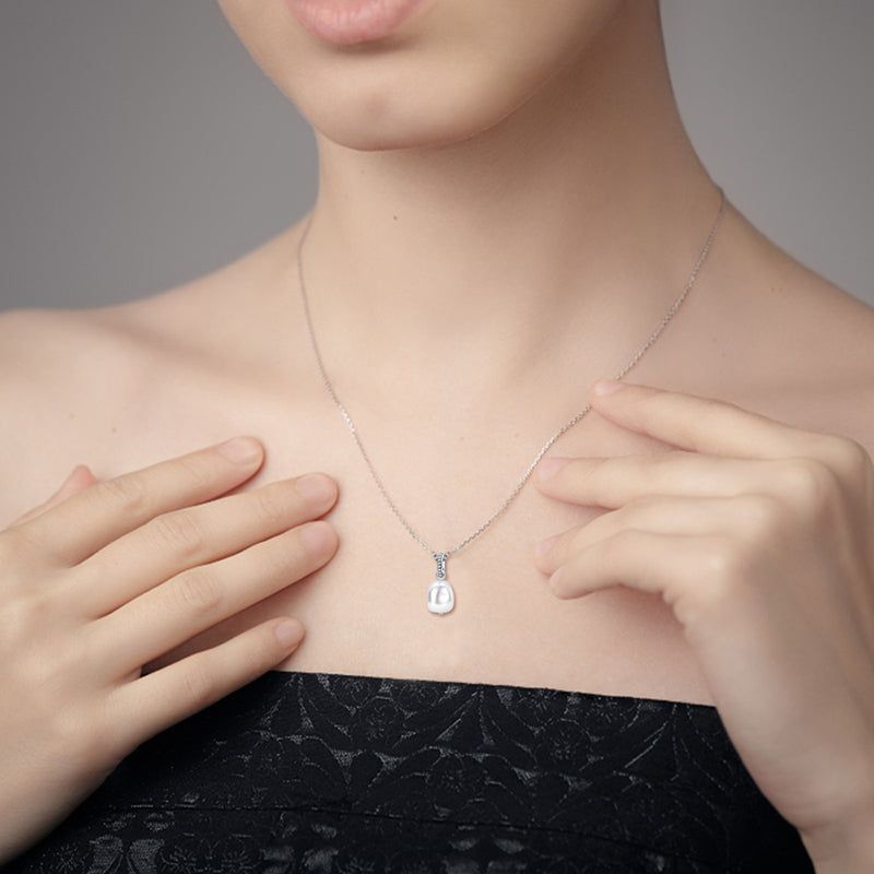 Woman wearing a silver necklace with a pearl pendant, showcasing its fit and style on the neckline.