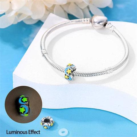  silver charm with a celestial design of yellow stars and blue moons on enamel.