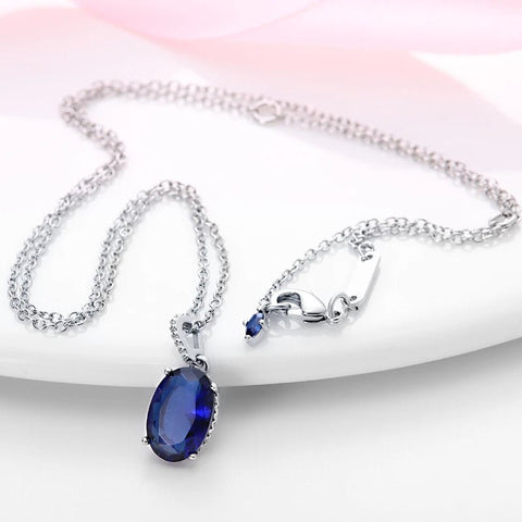 Elegant Blue Sapphire Oval Pendant Necklace in Sterling Silver with Cubic Zirconia Accents - Full view of a sterling silver necklace with a blue sapphire oval pendant, highlighting the chain and pendant design.