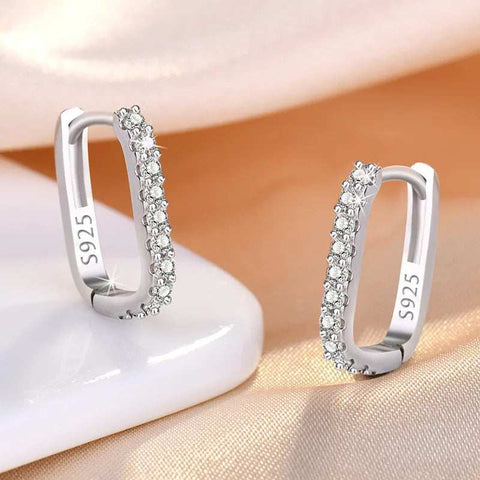 Elegant Sterling Silver Sparkling Hoop Earrings Pave Setting - Pair of silver hoop earrings with embedded cubic zirconia stones, displayed on a white surface with a soft fabric background.