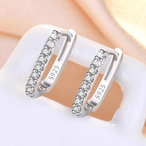 Pair of silver hoop earrings with embedded cubic zirconia stones, displayed on a white surface.