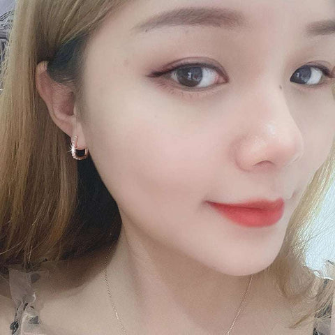 Elegant Sterling Silver Sparkling Hoop Earrings Pave Setting - Close-up of a woman with long blonde hair wearing small rose gold hoop earrings, highlighting her ear and cheek.