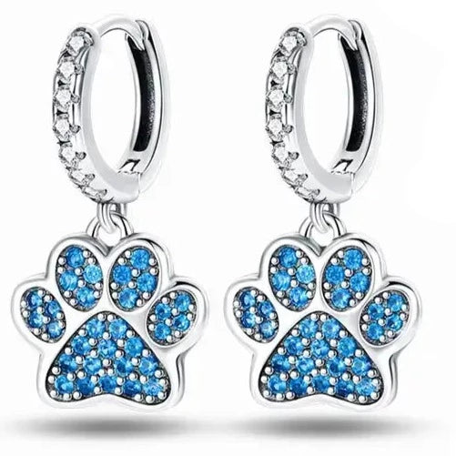 Silver paw print dangle earrings with blue crystals on a white background.