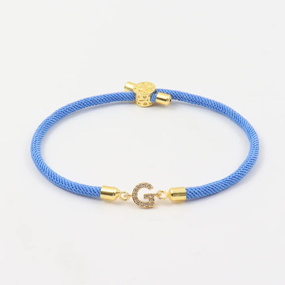 Customizable Initial Bracelet with Crystal Charm in Blue and Red - Blue cord bracelet with crystal initial charm and gold-tone accents.