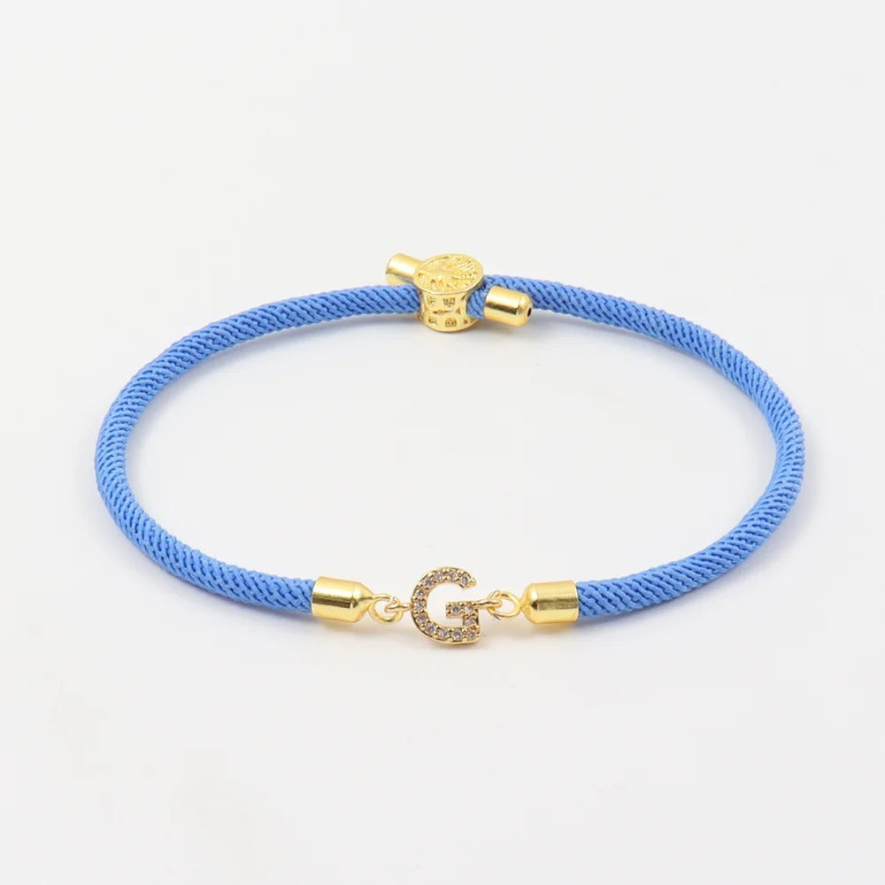 Blue cord bracelet with crystal initial charm and gold-tone accents.