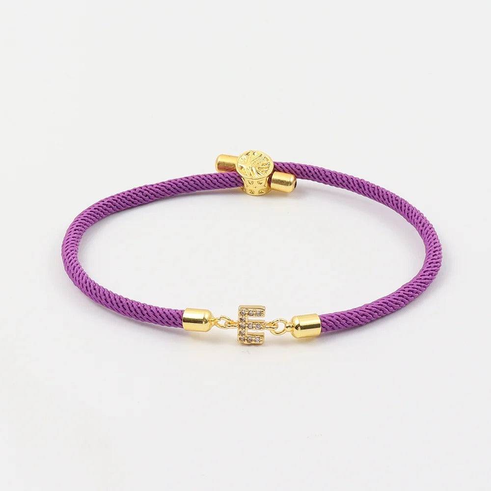 Purple cord bracelet with crystal initial charm and gold-tone accents.