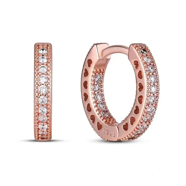 Rose gold huggie hoop earrings with sparkling cubic zirconia stones and heart-shaped cutouts.