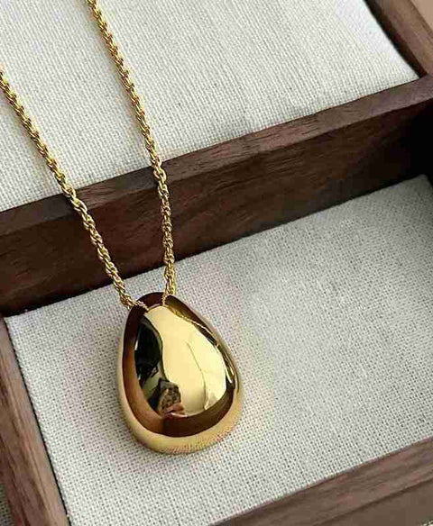 Chic Gold and Silver Teardrop Pendants for Every Occasion - a gold tear necklace on a wooden box