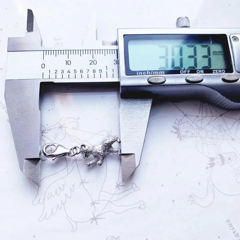 Silver dinosaur charm being measured.