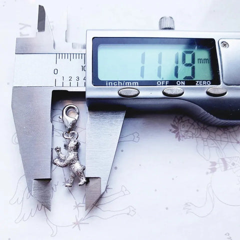 Silver bear charm being measured.