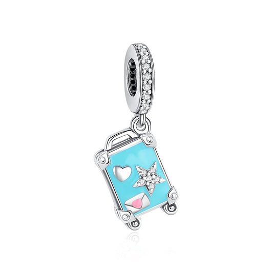 A silver-tone dangle charm shaped like a turquoise blue enamel mini suitcase decorated with a crystal star, white heart, and pink envelope, suspended from a pavé crystal bail