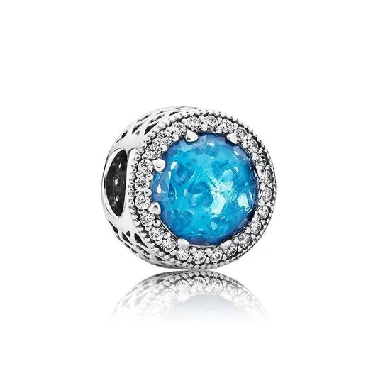 Sterling silver charm with blue aquamarine crystal center and halo of cubic zirconia stones.