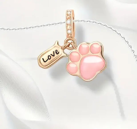 Close-up of a silver snake chain bracelet with a rose gold pink paw print charm and "Love" tag.