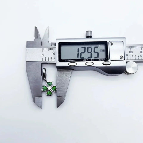 Green four-leaf clover charm being measured.