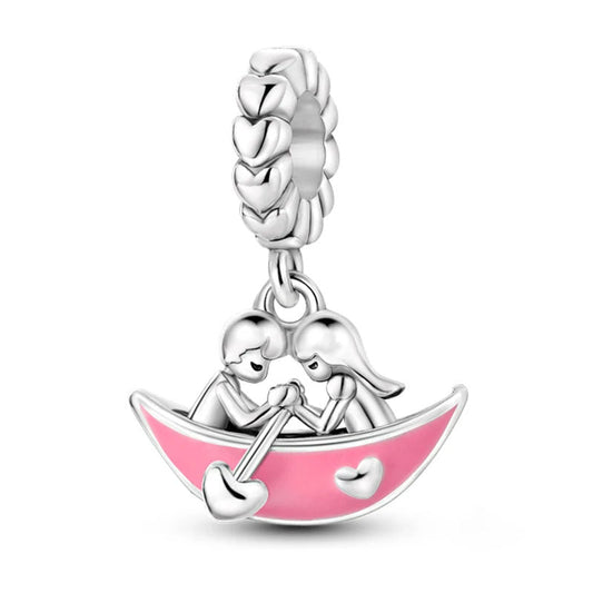 Silver couple in a boat charm with pink enamel accents.