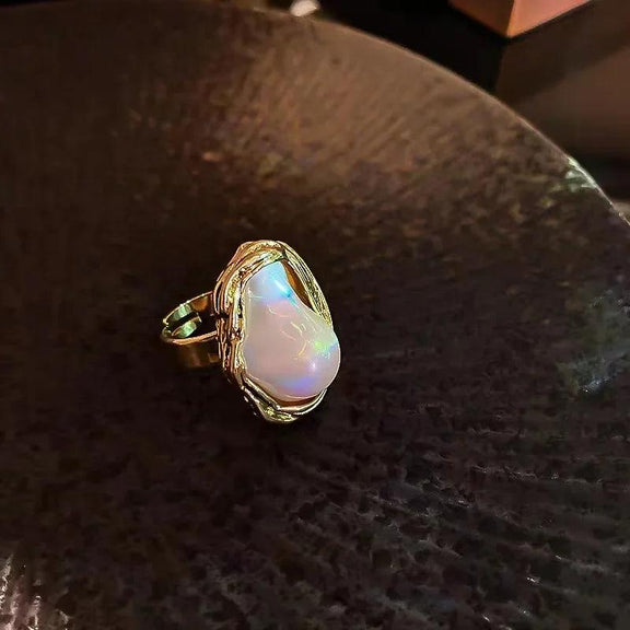 Adjustable Gold Ring with Unique Baroque Pearl - Close-up of a gold ring with a unique baroque pearl centerpiece, placed on a dark textured surface, showcasing its intricate details.