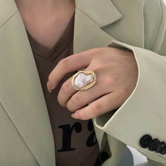 Adjustable Gold Ring with Unique Baroque Pearl - Woman wearing an elegant gold ring with a unique baroque pearl, complementing her stylish light green blazer and brown top.