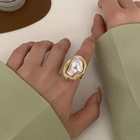 Adjustable Gold Ring with Unique Baroque Pearl - Woman's hand adorned with a gold ring featuring a unique baroque pearl, paired with a chic light green sleeve.