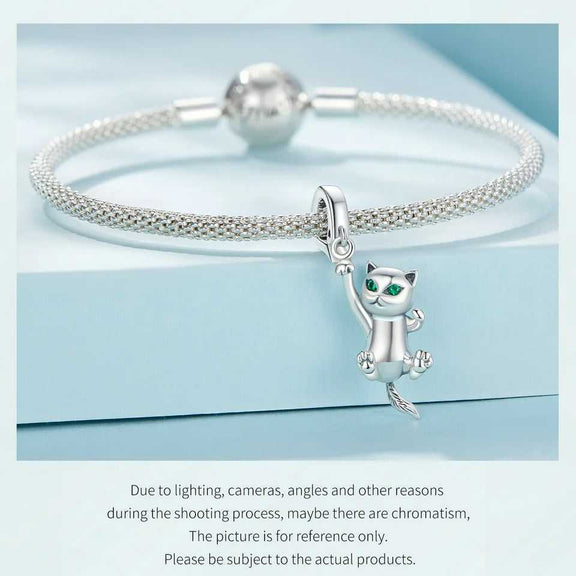 Sterling Silver Hanging Cat Charm with Emerald Eyes - Silver mesh bracelet with a hanging cat charm featuring emerald eyes, displayed on a light blue background.