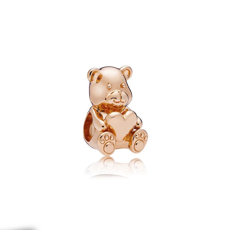 Rose gold bear charm holding a heart, perfect for charm bracelets or necklaces.