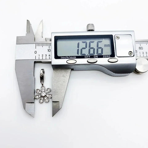 Silver flower charm being measured.