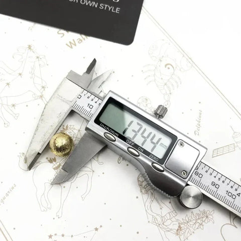 Digital caliper measuring a gold sphere.