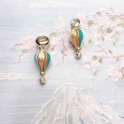 Two gold-trimmed, enameled hot air balloon charms.