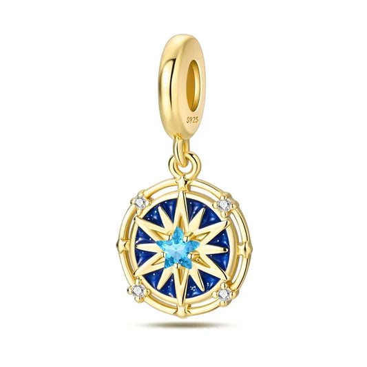 Sterling silver and gold compass star charm with a central blue crystal, surrounded by navy-blue enamel and sparkling crystals.