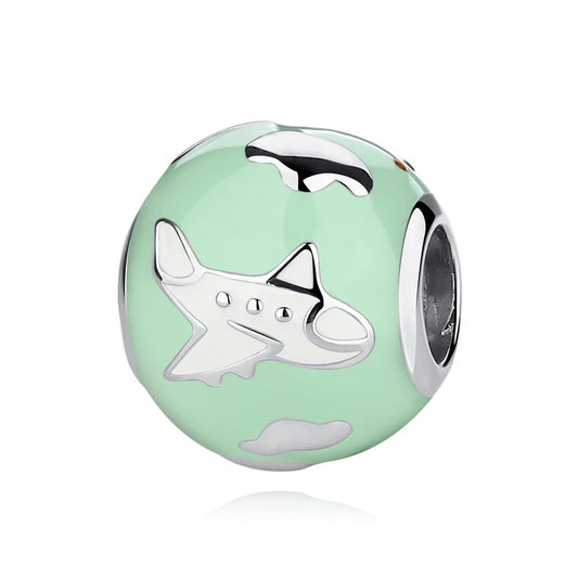 A round silver charm with mint-green enamel background featuring a raised silver airplane and white clouds, with a center hole for attaching to a charm bracelet