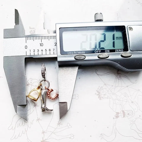 Jewelry charm measured by calipers.