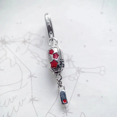 Silver lantern earring with red accents.