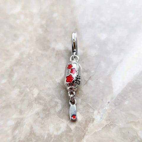 Silver lantern charm with red accents.