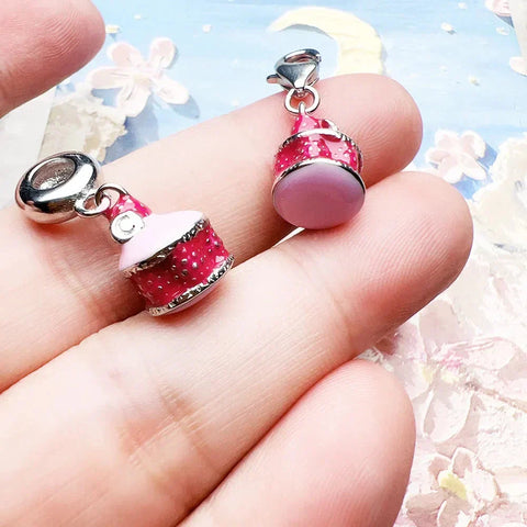 Two pink cake charm pendants.