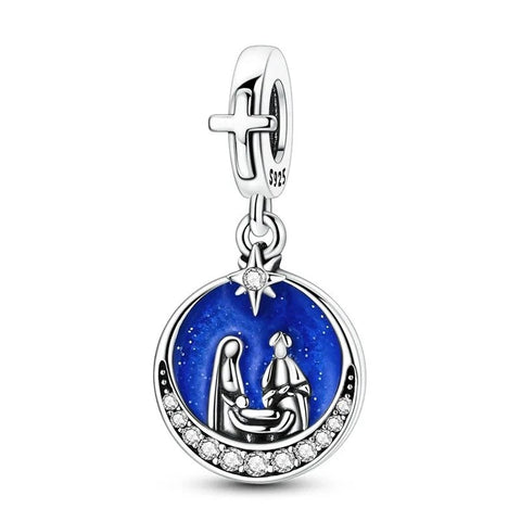 A sterling silver dangle charm featuring a circular blue enamel medallion with a nativity scene of Mary, Joseph and baby Jesus beneath a star, framed with clear crystals and topped with a cross bail