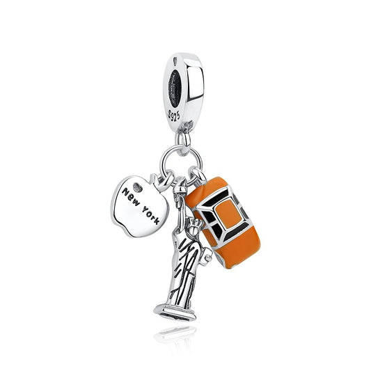 Silver S925 dangle charm with three pendants: a Statue of Liberty figurine, an engraved New York apple tag, and an orange enamel taxi cab