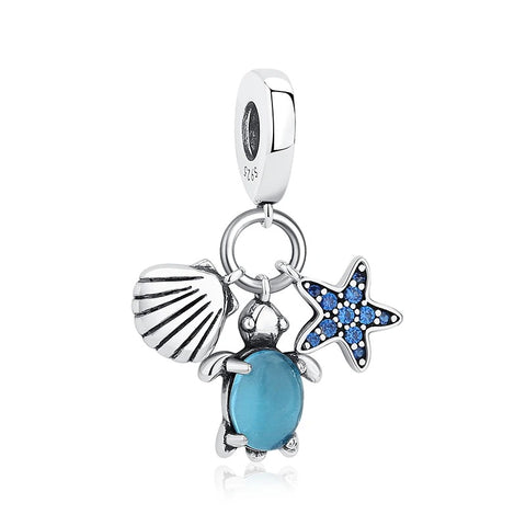 Ocean Trio Sea Turtle, Starfish & Shell Dangle Charm - Sterling silver dangle charm featuring three ocean pendants: a sea turtle with a blue oval gemstone, a blue cubic zirconia starfish, and a ridged scallop shell, hanging from a clip-on bail