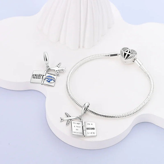 Sterling Silver Travel Charm with Passport and Airplane for Pandora Bracelets - Sterling silver charm for bracelets depicting a passport and airplane, embellished with cubic zirconia, designed to fit Pandora bracelets.