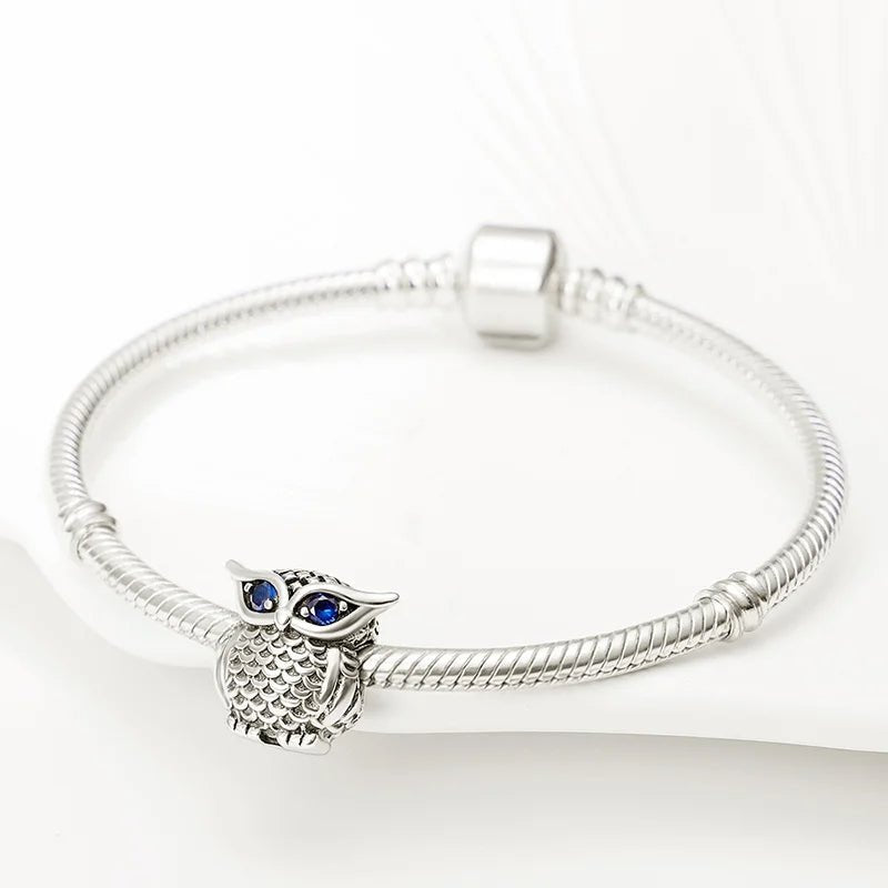 Owl charm made of sterling silver featuring sapphire blue eyes, fits Pandora.