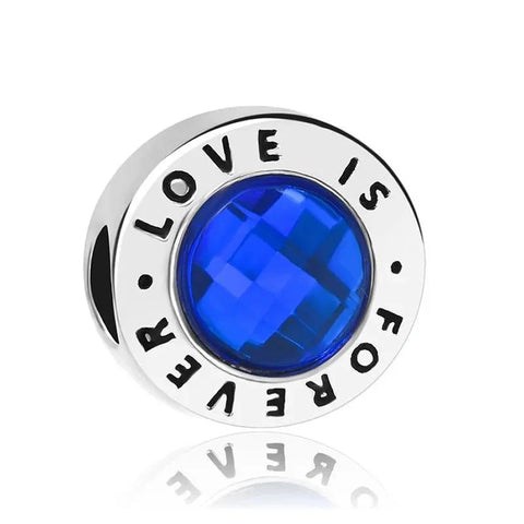 Sterling silver charm with a blue faceted crystal and engraved "Love Is Forever" message for a sentimental touch.