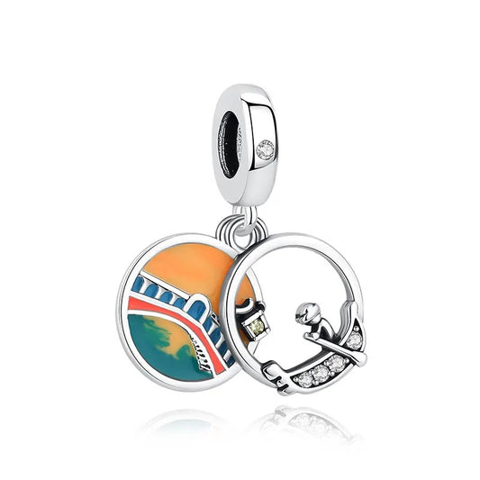 A silver clip-on charm featuring two hanging discs — one colorful enamel disc showing the Eiffel Tower at sunset, and one open silver ring charm depicting a gondolier with cubic zirconia accents