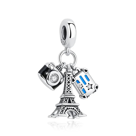 A sterling silver clip-on charm featuring three dangles: an oxidised Eiffel Tower, a black enamel camera with crystal lens, and a blue enamel suitcase with crystal details