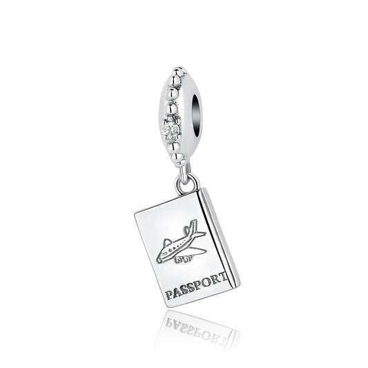 A silver dangle charm shaped like a passport booklet engraved with an airplane and the word PASSPORT, hanging from an oval CZ-studded bail, shown on a white background.