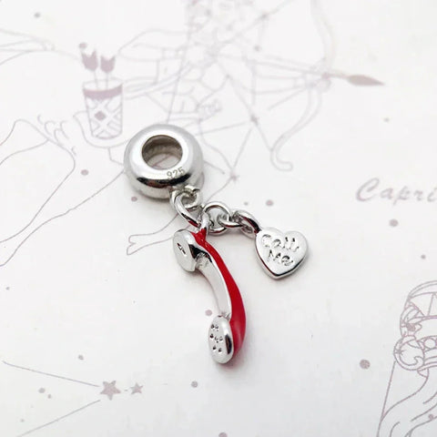 Silver charm with red telephone and heart.