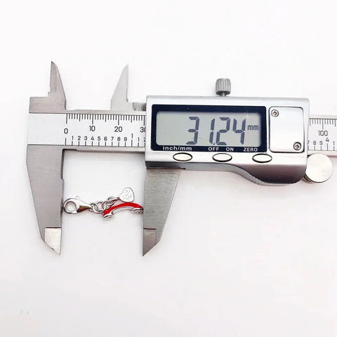 Silver and red charm being measured.