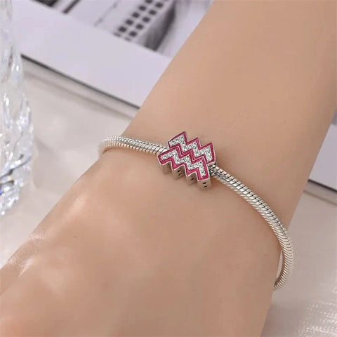 Silver charm bracelet with Aquarius symbol.