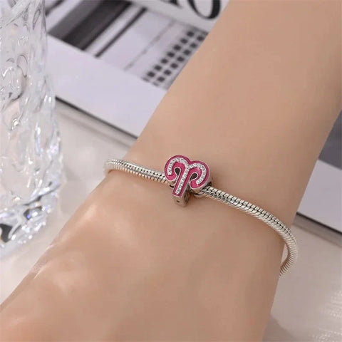 Silver charm bracelet with pink Aries pendant.