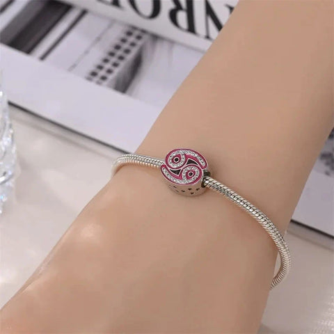 Silver bracelet with a red and white Cancer zodiac charm.