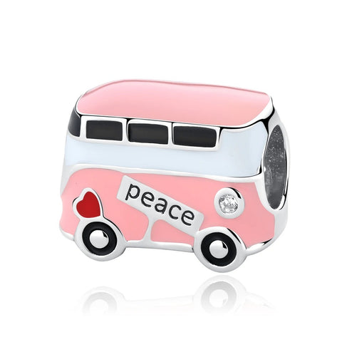 A silver-tone charm shaped like a retro pink and white bus with black windows, black wheels, a red heart, a clear crystal, and the word peace inscribed on the side