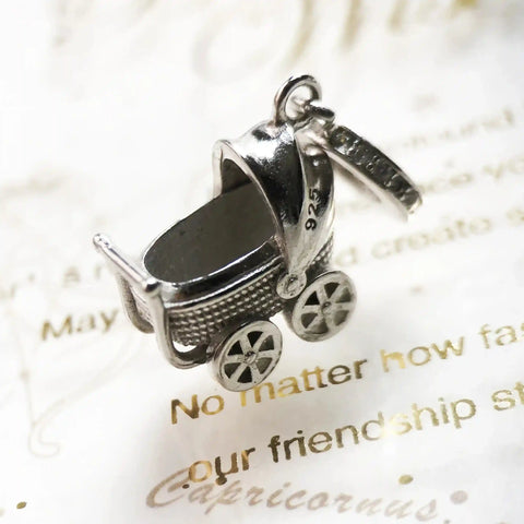 Silver baby carriage charm.